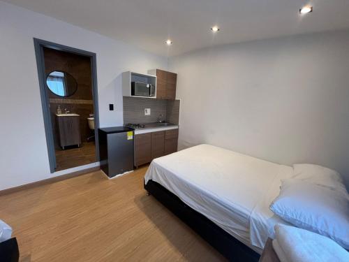 a bedroom with a white bed and a kitchen at Loft Recuerdos de mi tierra in Medellín