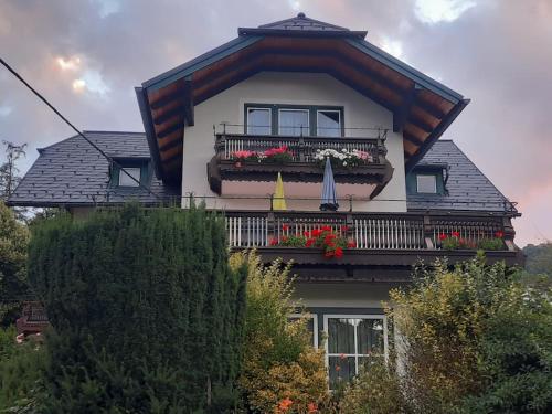 a house with a balcony with flowers and an umbrella at Ferienwohnung direkt am See 3 in Altmünster