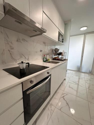 a kitchen with white cabinets and a stove top oven at Pereira Azurara 3 quarto 3D in Póvoa de Varzim