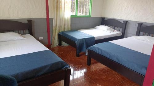 a room with two beds and a window at FINCA HOTEL LAS CABAÑAS DEL Parque in Pueblo Tapao