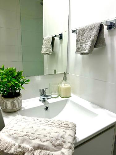 a white bathroom with a sink and a mirror at Departamento Estudio in Concepción