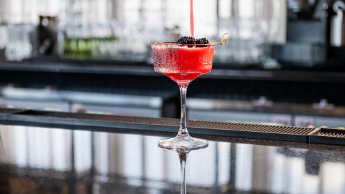 a red drink in a wine glass sitting on a table at Vetta, Distrito Uno, Autograph Collection in Chihuahua
