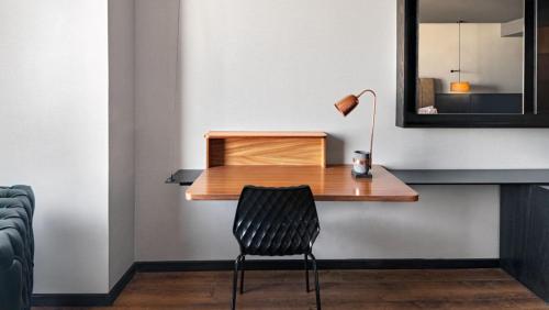 a desk with a lamp and a chair in a room at Vetta, Distrito Uno, Autograph Collection in Chihuahua