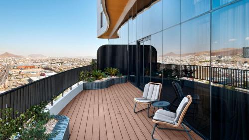 a balcony with two chairs and a view of a city at Vetta, Distrito Uno, Autograph Collection in Chihuahua