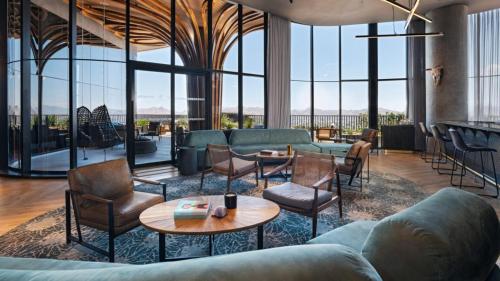 a lobby with couches chairs and tables and windows at Vetta, Distrito Uno, Autograph Collection in Chihuahua