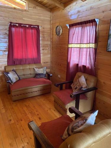 a living room with two chairs and red curtains at Cabaña Girasoles - CUTE Cabin with Amaizing views! in Jardín