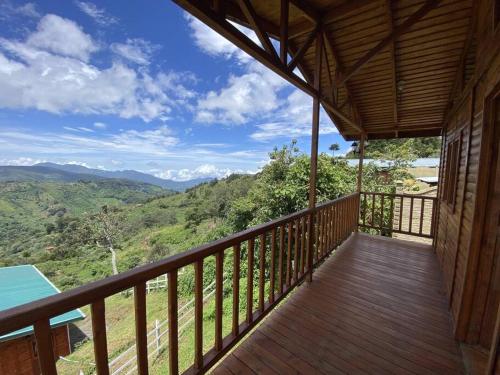 a wooden balcony with a view of the mountains at Cabaña Girasoles - CUTE Cabin with Amaizing views! in Jardín
