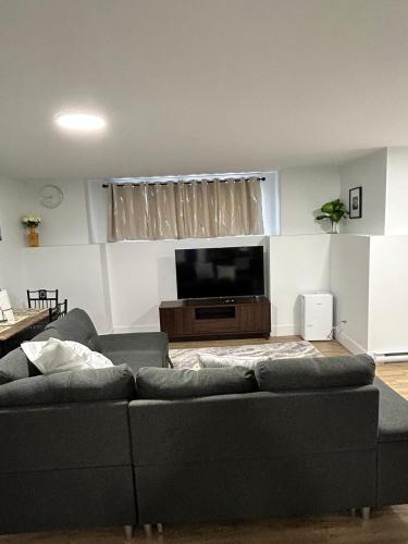 a living room with a couch and a flat screen tv at Cozy Bedroom Apartment in Moncton North in Moncton