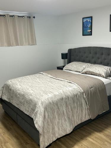 a bedroom with a large bed with a gray headboard at Cozy Bedroom Apartment in Moncton North in Moncton