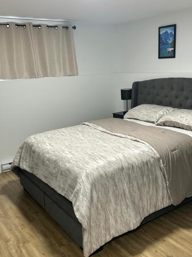 a bedroom with a large bed with a gray headboard at Cozy Bedroom Apartment in Moncton North in Moncton