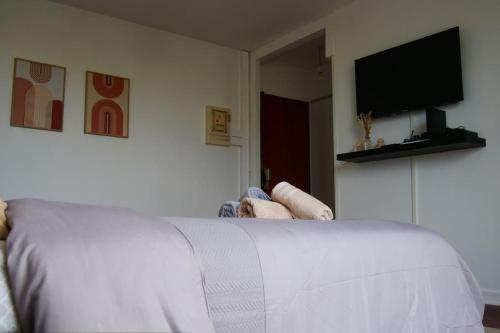 a bedroom with a white bed and a flat screen tv at Studio Cosy proche Métro in Aubervilliers