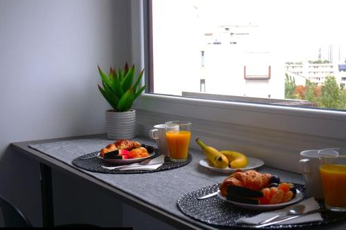 a table with two plates of food and two glasses of orange juice at Studio Cosy proche Métro in Aubervilliers