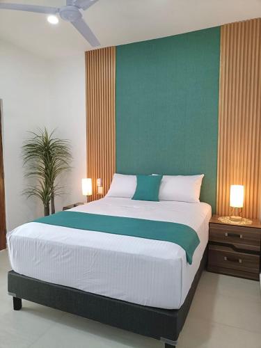 a bedroom with a large bed with a green wall at Hotel Punta Colibrí in Puerto Escondido