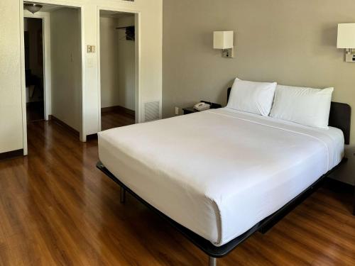a large white bed in a room with wooden floors at Motel 6-Pomona, CA - Los Angeles in Pomona
