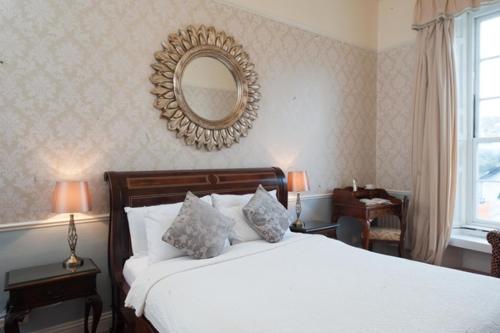 a bedroom with a large bed and a mirror at The Old Bank Town House in Kinsale