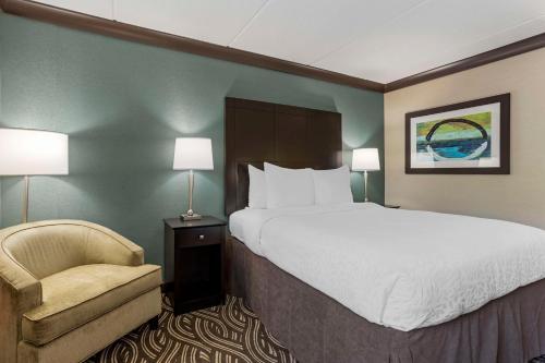 a hotel room with a large bed and a chair at Best Western Plus Kingston Hotel and Conference Center in Kingston