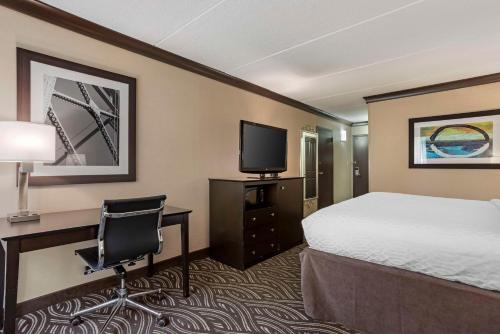 a hotel room with a bed and a desk and a television at Best Western Plus Kingston Hotel and Conference Center in Kingston