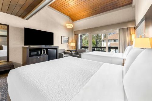 a hotel room with a bed and a flat screen tv at Best Western Plus Banff International Lodge in Banff
