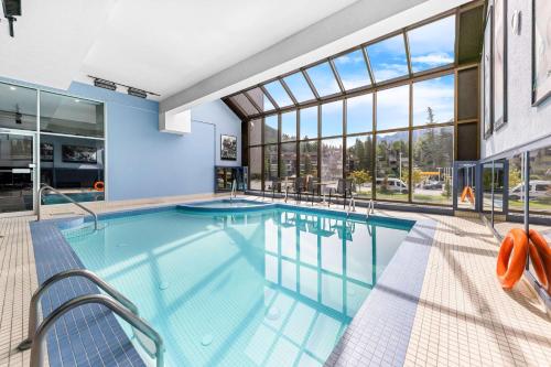 a swimming pool in a building with glass windows at Best Western Plus Banff International Lodge in Banff