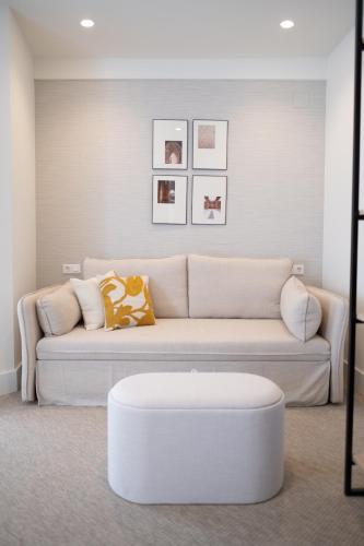 a white living room with a couch and a stool at Hotel Cetina Casa de Aguilar in Córdoba