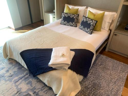 a large bed with blue and white sheets and pillows at Te Whaanga Retreat & Spa in Raglan