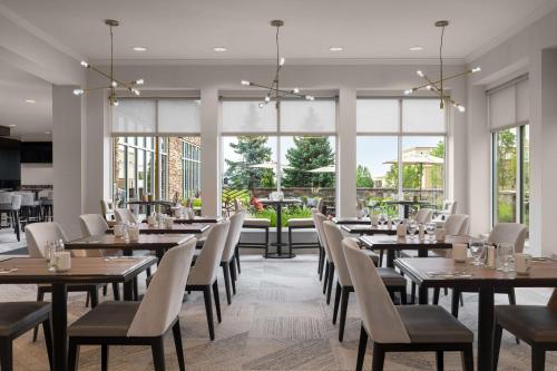 a dining room with tables and chairs and windows at Hilton Garden Inn Great Falls in Great Falls