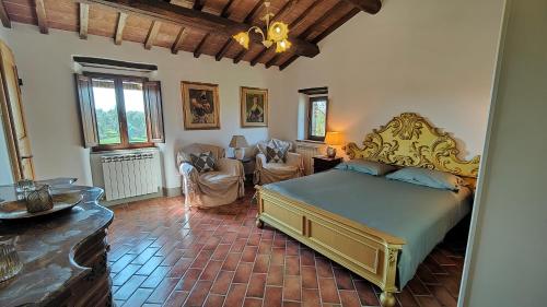 a bedroom with a bed and chairs in a room at Casale Alcinoo - Rustico in Tuoro sul Trasimeno