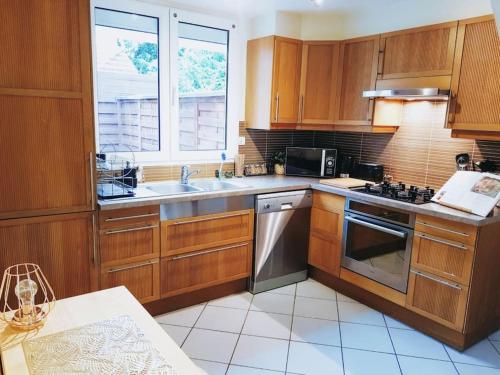 une cuisine avec des armoires en bois et un évier dans l'établissement Charmant Pavillon - 15 min de Paris - Gare à 300 m, à Cormeilles-en-Parisis