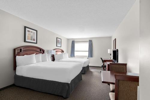a hotel room with two beds and a television at SureStay Plus Hotel by Best Western Hardisty in Hardisty
