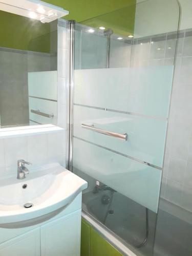 une salle de bain blanche avec un lavabo et une douche dans l'établissement Location appartement 3 pièces à 200 m de la gare 5 pers max, à Cormeilles-en-Parisis