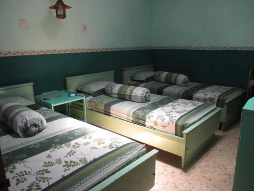 3 camas en una habitación con paredes verdes en Hotel Anugerah Bondowoso, en Bondowoso