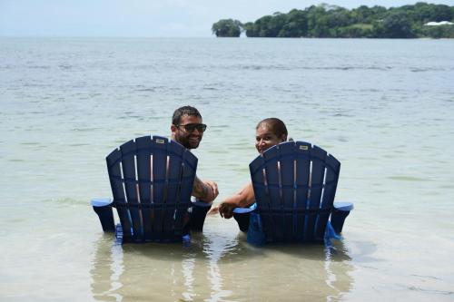 a man and a child sitting in chairs in the water at Drago Beach House - Private Beach in Boca del Drago