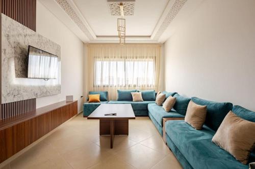 a living room with a blue couch and a table at Residence GYA Beach - Luxe Moderne et Confort à Harhoura accès plage in Temara