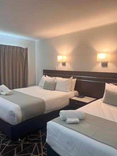 a hotel room with two beds with towels on them at Auckland Airport Kiwi Hotel in Auckland