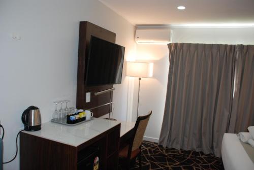 a hotel room with a desk and a flat screen tv at Auckland Airport Kiwi Hotel in Auckland