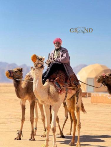 a man riding on a camel in the desert at Wadi Rum Grand in Wadi Rum