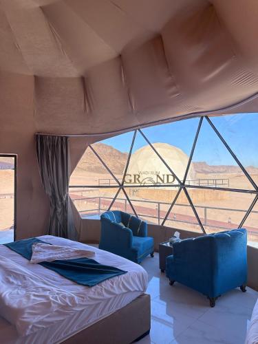 a bedroom with a bed and two chairs and a window at Wadi Rum Grand in Wadi Rum
