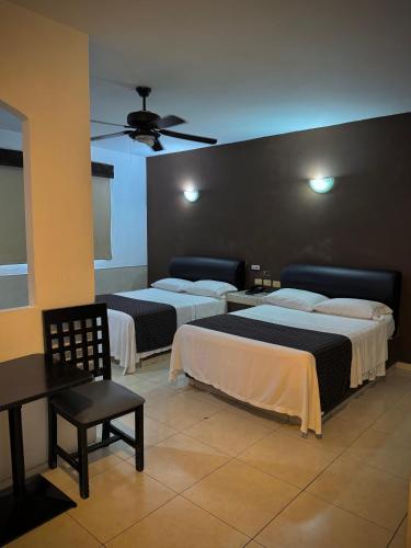a hotel room with two beds and a chair at Hotel Maioris Kumate Culiacán in Culiacán