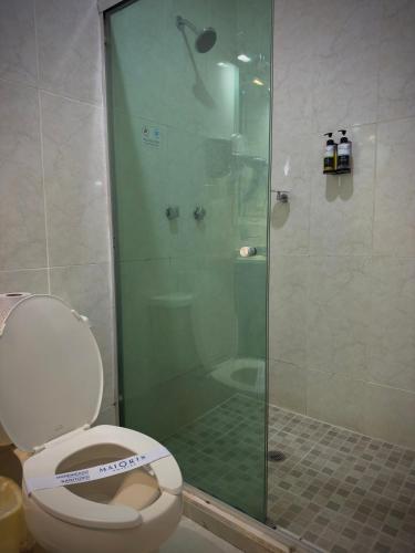 a bathroom with a toilet and a glass shower at Hotel Maioris Kumate Culiacán in Culiacán
