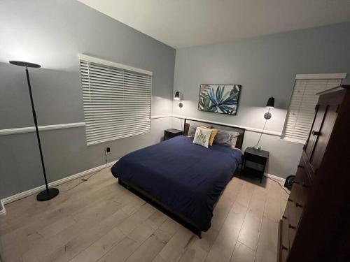 a bedroom with a bed and two lamps and two windows at Pet Friendly Home Near Hospitals in Moreno Valley