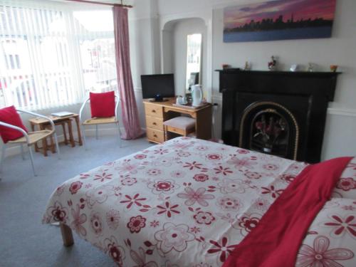 a bedroom with a red and white bed and a fireplace at Ty Newydd Guest House in Trefriw