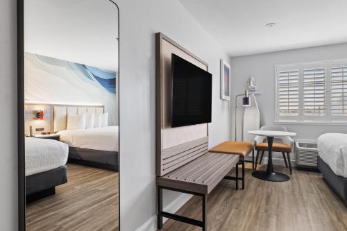 a hotel room with a bench with a flat screen tv at Hotel Skye San Francisco Airport SFO FREE SHUTTLE! in San Bruno