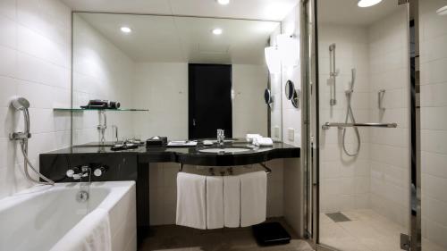 a bathroom with a tub and a sink and a shower at RISONARE Osaka in Osaka