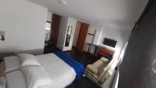 a bedroom with a white bed and a television at Camino A La Villa Cucaita Hotel in Cucaita