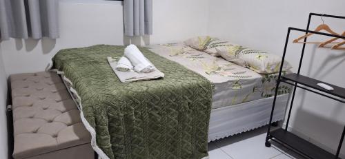 a bed with a green blanket and towels on it at Ap 2 quartos tipo resort pé na areia 1 in Barra dos Coqueiros