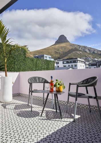 a table and chairs on a patio with a mountain in the background at Pineapple House Boutique Hotel in Cape Town
