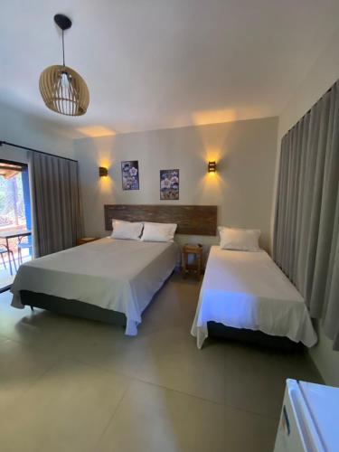 a bedroom with two beds and a window at Pousada Cigarras da Serra in Serra do Cipo