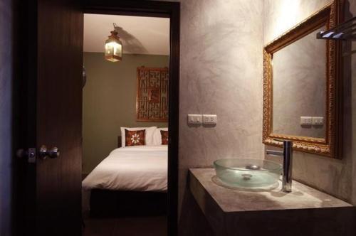 uma casa de banho com um lavatório, uma cama e um espelho. em Lilu Chiang Mai em Chiang Mai