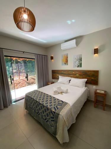 a bedroom with a large bed and a large window at Pousada Cigarras da Serra in Serra do Cipo