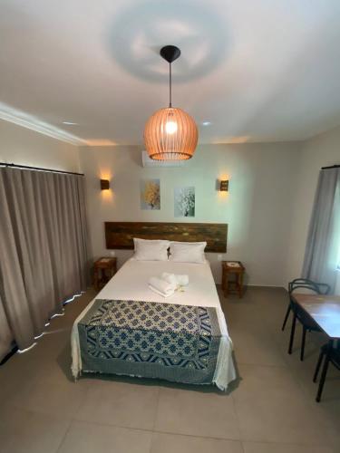 a bedroom with a large bed and a chandelier at Pousada Cigarras da Serra in Serra do Cipo